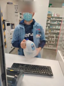 Costco Pharmacy pharmacist holding a Morning Mist 1-gallon distilled water jug at the prescription counter in Mississauga
