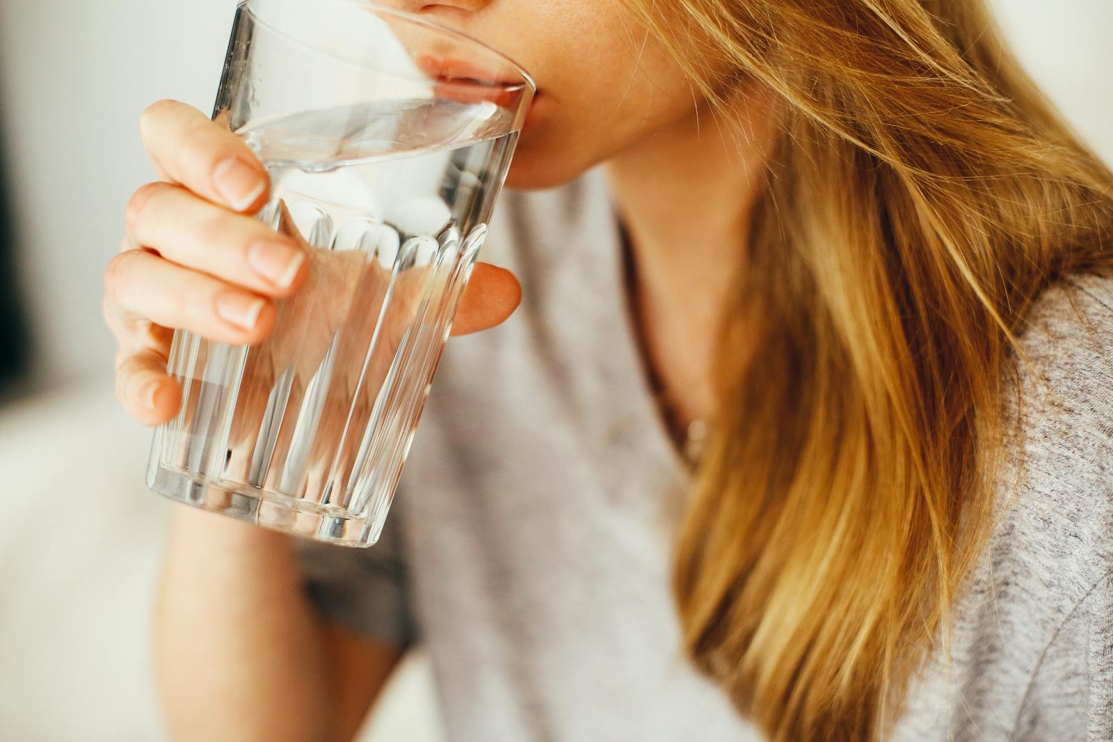 Woman drinking a tall glass of fresh water for daily hydration