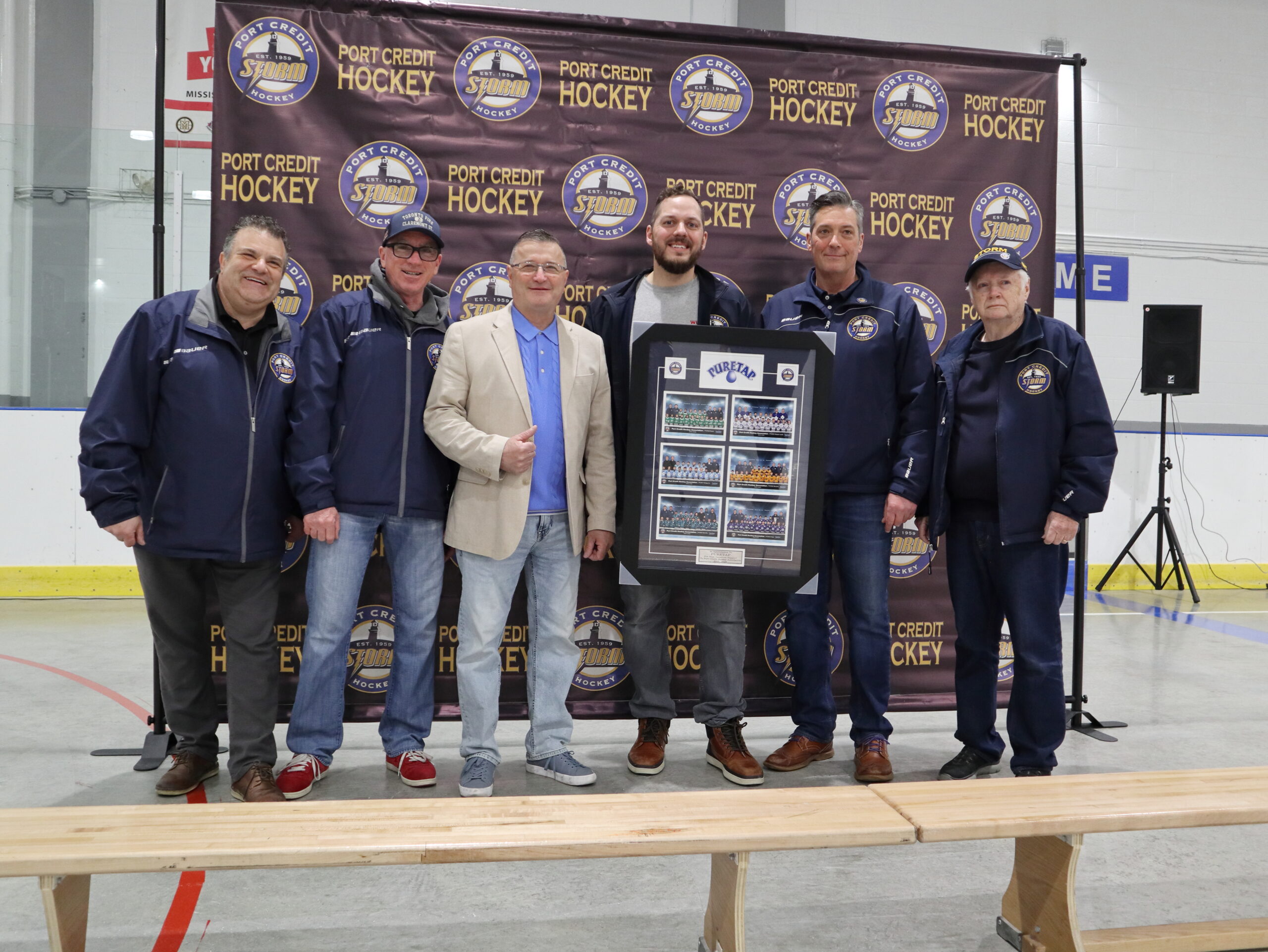 Port Credit Hockey volunteers and organizers presenting a framed seasonal photo collage in front of the Port Credit Hockey backdrop at the 2026 PCHA Awards Ceremony at Port Credit Memorial Arena.