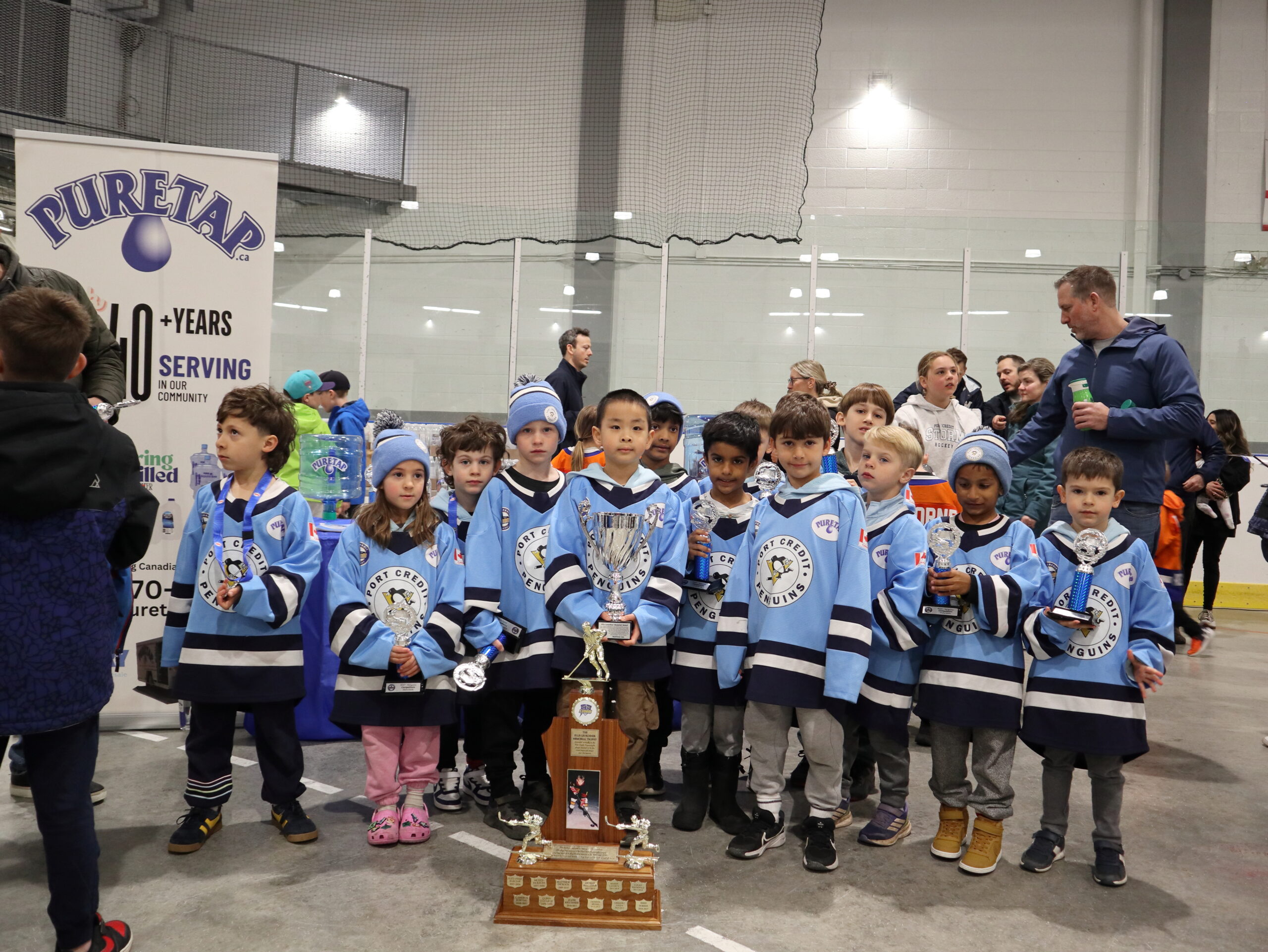 Light blue and white youth hockey team posed behind their large team trophy with the Puretap banner clearly visible at the 2026 Port Credit Hockey Awards Ceremony.